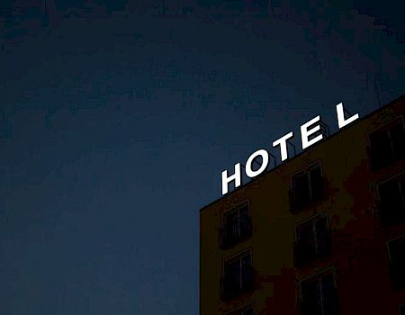A building with a "HOTEL" sign is visible against a dark sky, with the "L" slightly detached.