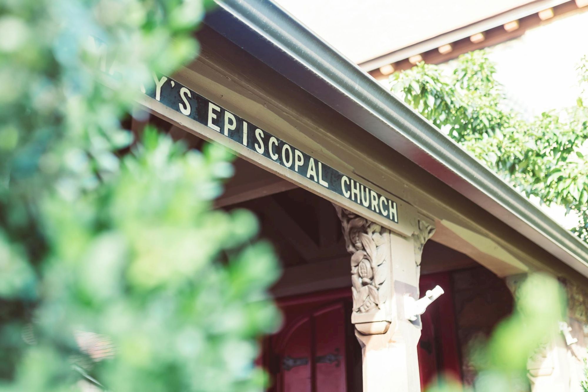The image shows the entrance of a building with a sign reading "EPISCOPAL CHURCH," partially obscured by greenery.
