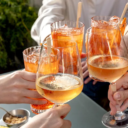 A group toasting with cocktails and wine glasses, clinking drinks outdoors to celebrate together.
